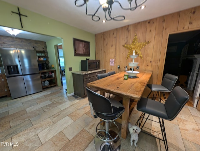 dining area featuring wooden walls and a chandelier