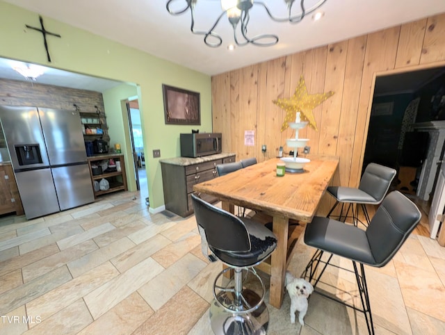 dining area with an inviting chandelier and wood walls