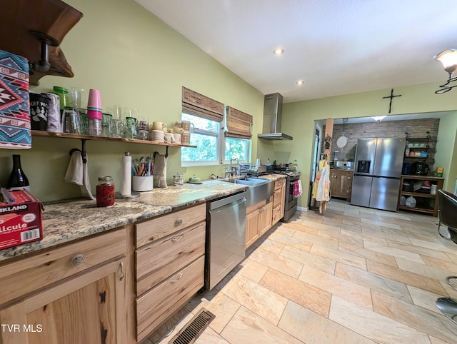 kitchen with light stone counters, stainless steel appliances, wall chimney exhaust hood, and sink