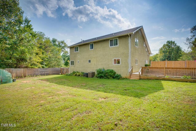 rear view of property with central air condition unit and a yard