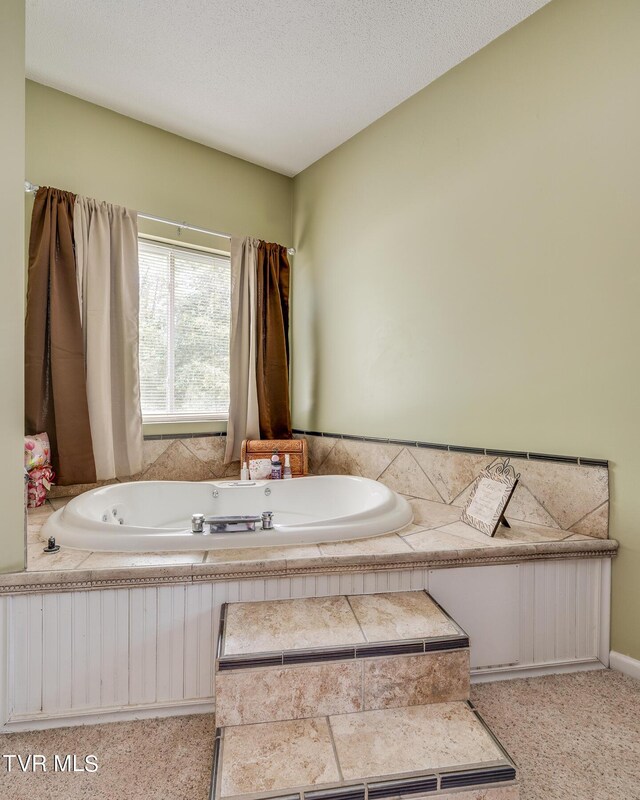 bathroom with a textured ceiling and a tub