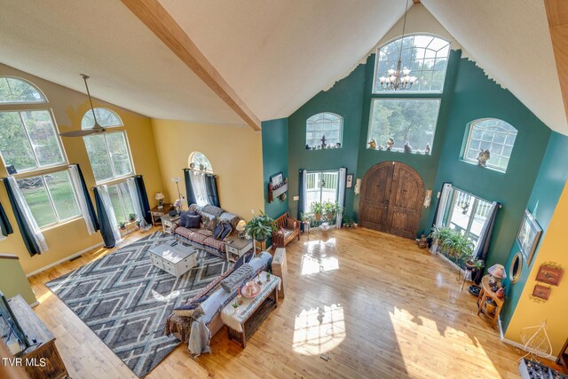 living room with a healthy amount of sunlight, light hardwood / wood-style floors, and high vaulted ceiling