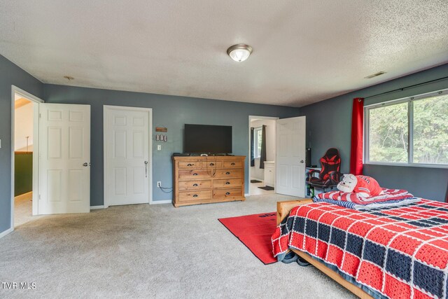 bedroom with carpet, a textured ceiling, and ensuite bathroom