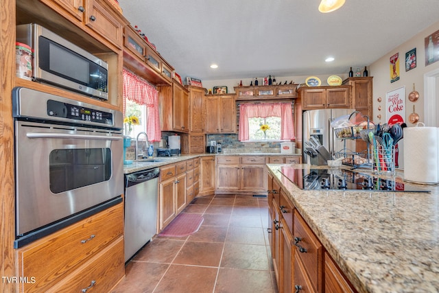 kitchen with light stone countertops, stainless steel appliances, plenty of natural light, and sink