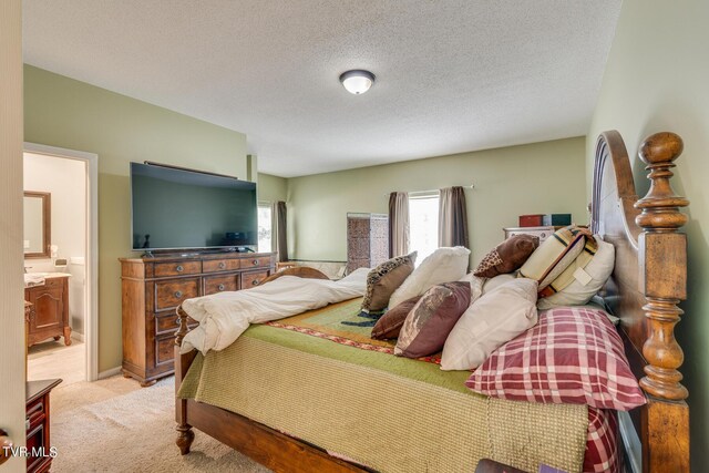 carpeted bedroom featuring a textured ceiling and ensuite bathroom