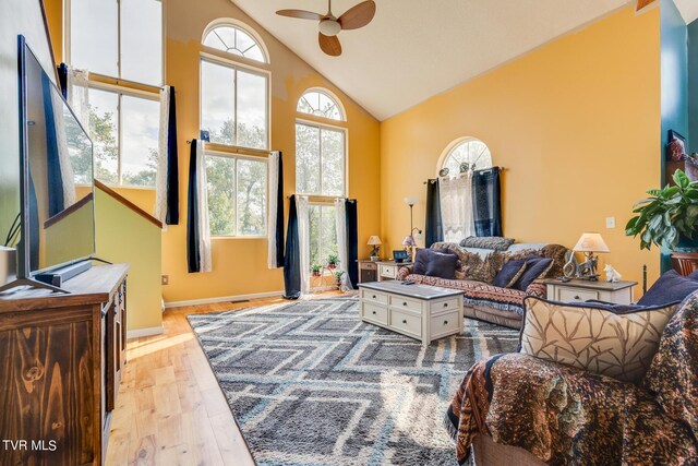 living room with ceiling fan, light hardwood / wood-style flooring, and high vaulted ceiling