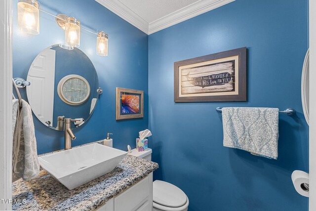 bathroom with a textured ceiling, crown molding, vanity, and toilet