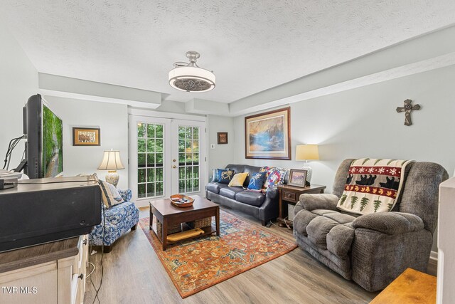 living room with a textured ceiling, hardwood / wood-style floors, and french doors