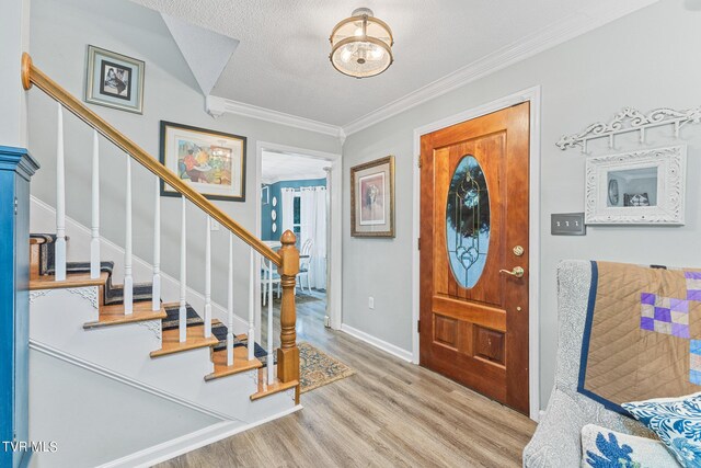 entrance foyer featuring ornamental molding, a textured ceiling, and light hardwood / wood-style floors