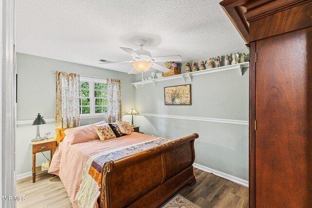 bedroom featuring a textured ceiling, ceiling fan, and hardwood / wood-style flooring