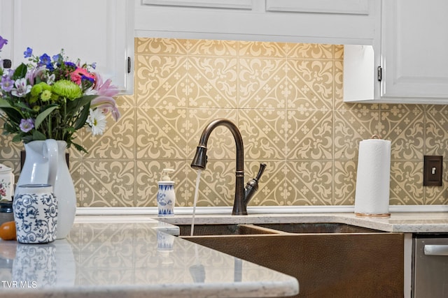 interior details featuring white cabinets, light stone counters, dishwasher, and sink