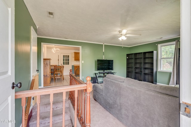 living room with a textured ceiling, carpet floors, ceiling fan, and crown molding