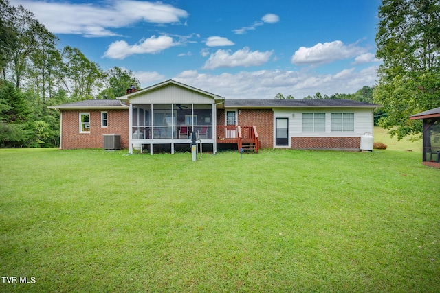 rear view of property featuring a wooden deck, a sunroom, a lawn, and central AC