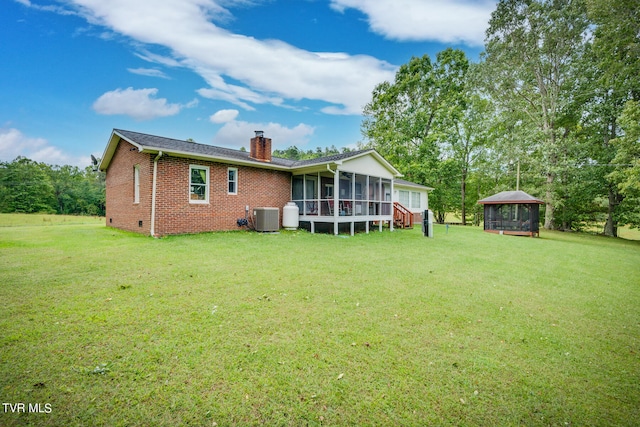 rear view of property with cooling unit, a gazebo, a sunroom, and a lawn