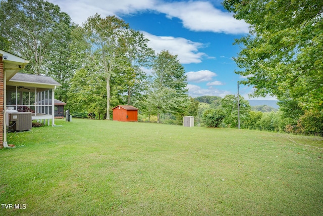 view of yard with a shed, a sunroom, and central AC unit