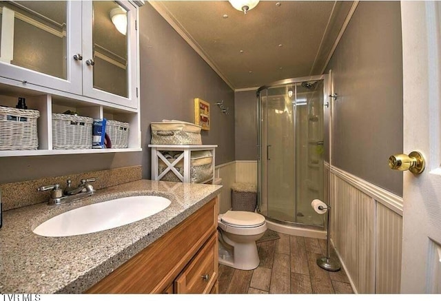 bathroom featuring vanity, wood-type flooring, walk in shower, crown molding, and toilet