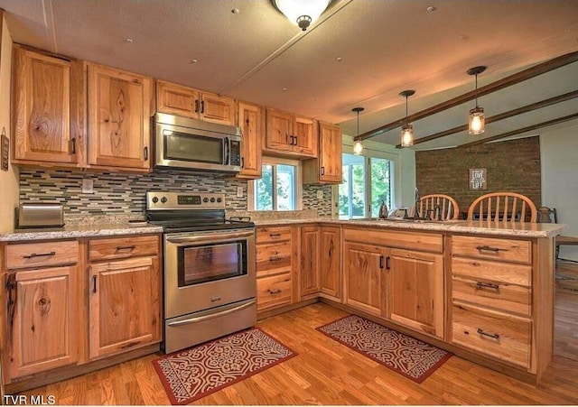 kitchen with stainless steel appliances, kitchen peninsula, hanging light fixtures, and light wood-type flooring