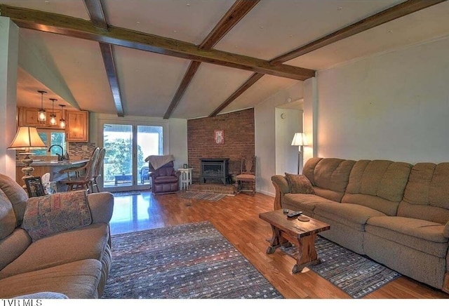 living room with lofted ceiling with beams, a wood stove, and light hardwood / wood-style flooring