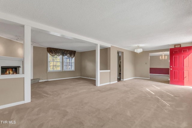 unfurnished living room featuring a textured ceiling, carpet, and a notable chandelier