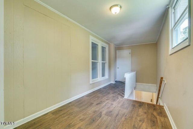 empty room with ornamental molding, baseboards, and wood finished floors