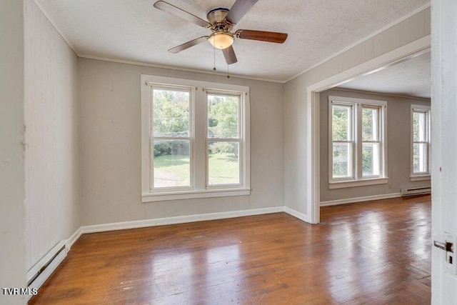 empty room featuring crown molding, wood finished floors, baseboard heating, and a textured ceiling