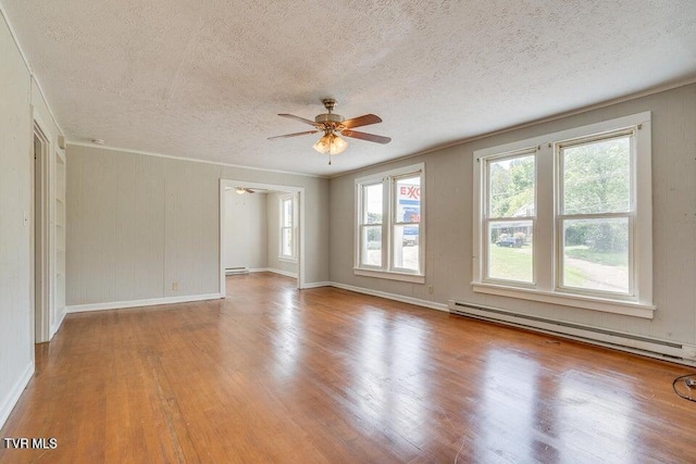 spare room featuring ornamental molding, a baseboard heating unit, a textured ceiling, wood finished floors, and ceiling fan