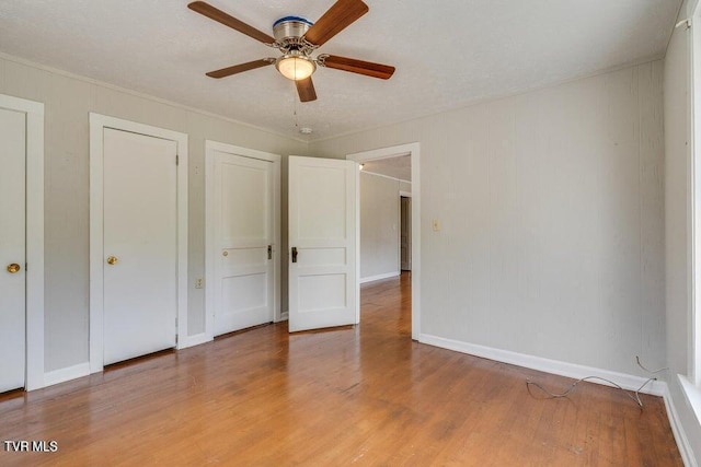 unfurnished bedroom with light wood finished floors, ceiling fan, crown molding, and baseboards