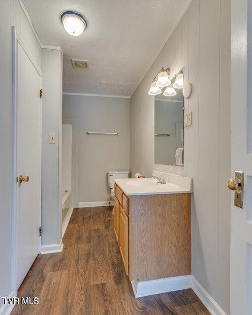 full bathroom with visible vents, wood finished floors, baseboards, walk in shower, and vanity