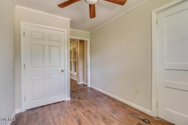 unfurnished bedroom featuring crown molding, wood finished floors, baseboards, and ceiling fan