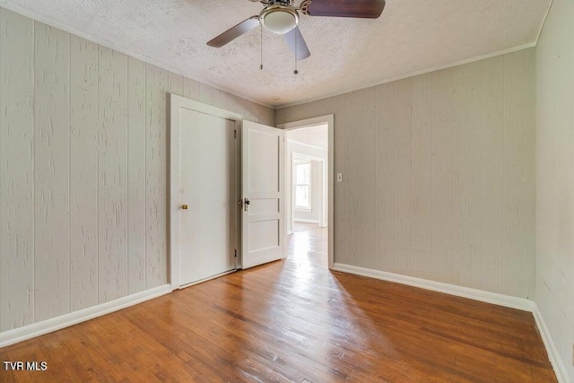 spare room with wood finished floors, baseboards, and a textured ceiling