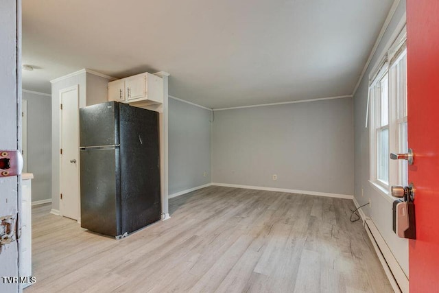 kitchen with light wood finished floors, a baseboard radiator, freestanding refrigerator, ornamental molding, and white cabinetry