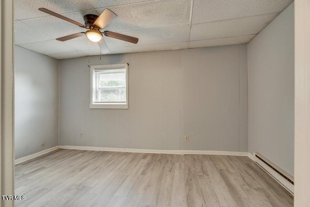 empty room with a baseboard heating unit, a paneled ceiling, and wood finished floors