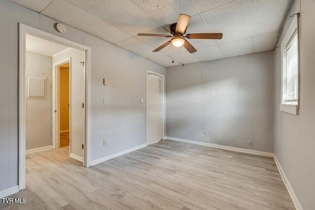 spare room with light wood-style flooring, a ceiling fan, baseboards, and a paneled ceiling