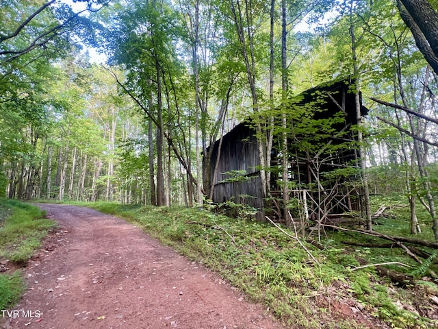 view of property's community with driveway, an outdoor structure, and a forest view