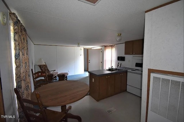 kitchen featuring white electric range, a textured ceiling, a peninsula, visible vents, and a sink