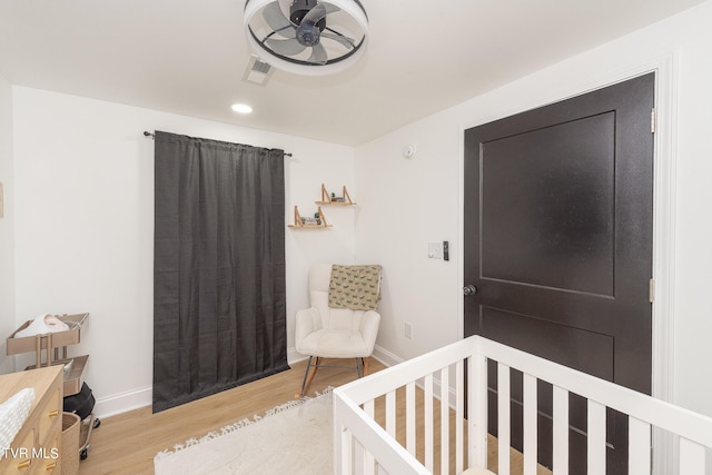 bedroom featuring a crib and light wood-type flooring