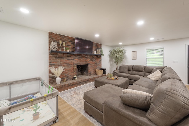 living room featuring light wood-type flooring and a brick fireplace