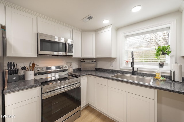 kitchen with white cabinetry, sink, light hardwood / wood-style flooring, and appliances with stainless steel finishes