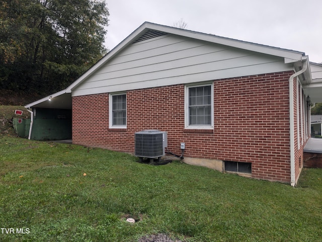 view of side of property featuring central air condition unit and a lawn