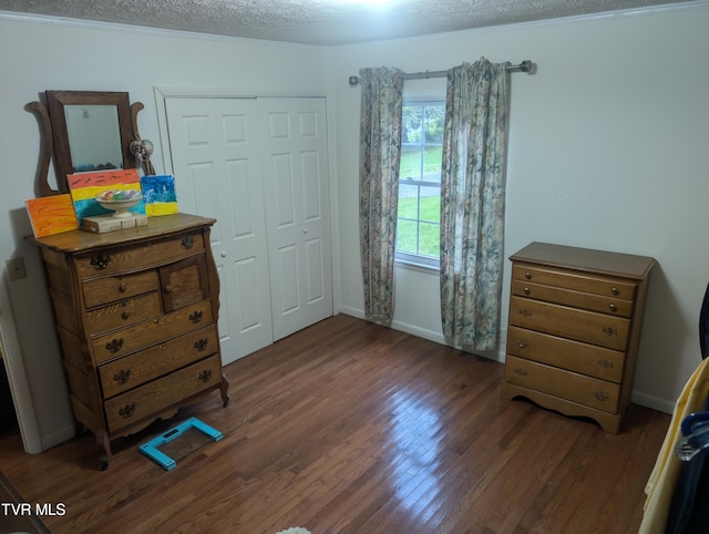 bedroom with a closet, a textured ceiling, dark hardwood / wood-style flooring, and ornamental molding