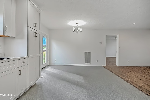 unfurnished room featuring a textured ceiling, ceiling fan with notable chandelier, and light hardwood / wood-style floors