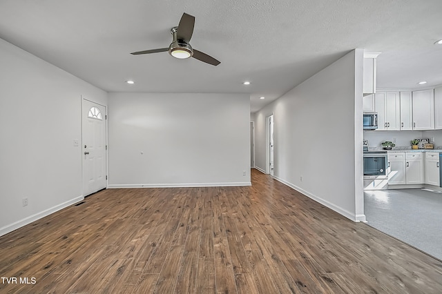 unfurnished living room with a textured ceiling, wood-type flooring, and ceiling fan