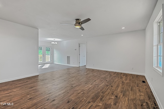 unfurnished room with ceiling fan with notable chandelier and dark wood-type flooring