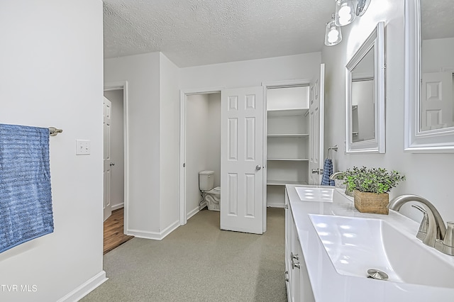 bathroom with a textured ceiling, vanity, and toilet