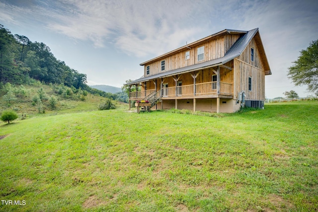 back of property with covered porch, central air condition unit, and a yard