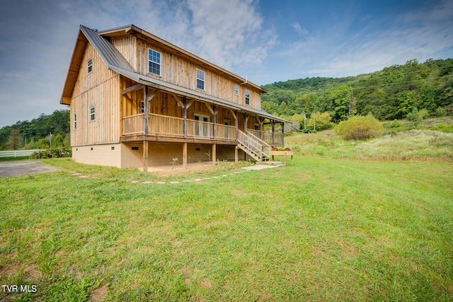 back of property featuring covered porch and a lawn