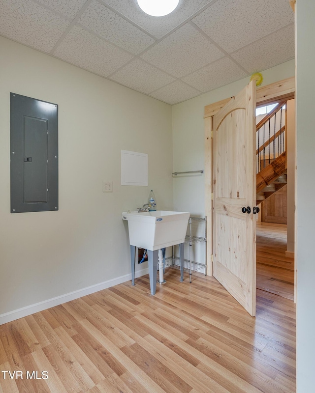 unfurnished office with electric panel, baseboards, wood finished floors, and a paneled ceiling