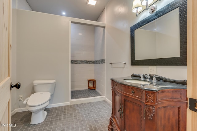 bathroom with toilet, vanity, tile patterned floors, and tiled shower