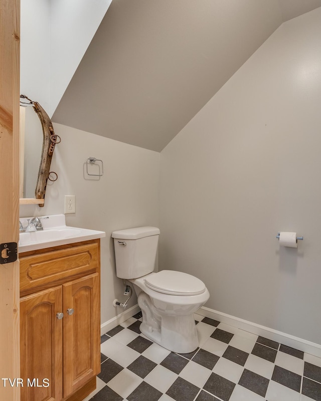 bathroom featuring vaulted ceiling, tile patterned floors, toilet, and vanity