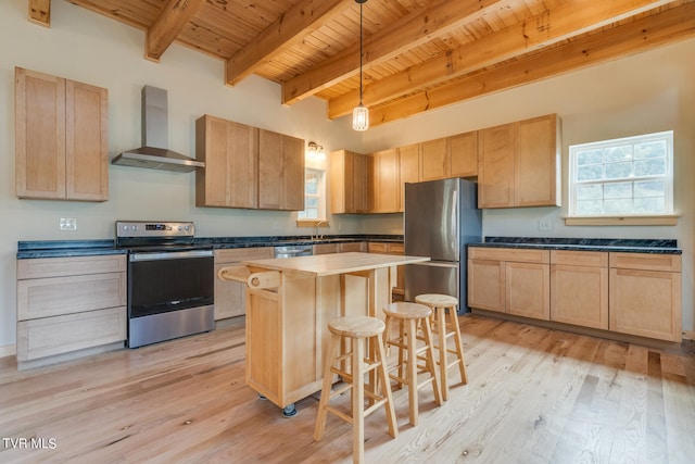 kitchen with wall chimney exhaust hood, a center island, appliances with stainless steel finishes, and a wealth of natural light